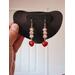 Light Pink Beaded Dangle Earrings with Small Red Heart Charm dangles on a jewelry display, as if they are worn.